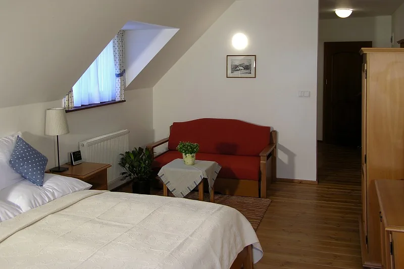 Podkrovná izba s posteľou a červeným kreslom